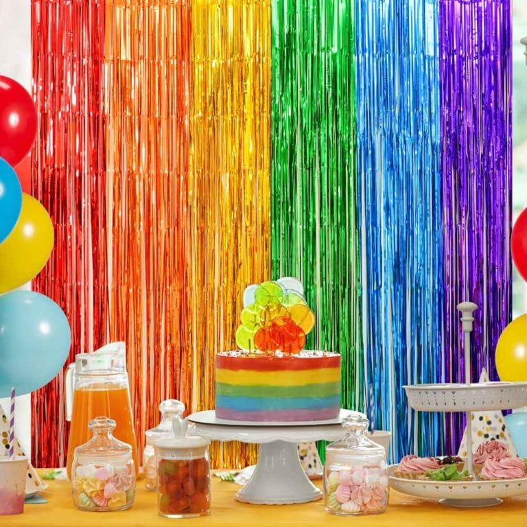 Rainbow Foil Fringe Curtain backdrop with cake and balloons for party