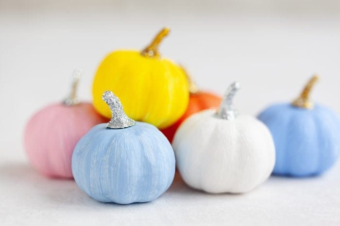 paint pumpkins in vibrant hues like purple, blue, yellow, and pink for a modern twist