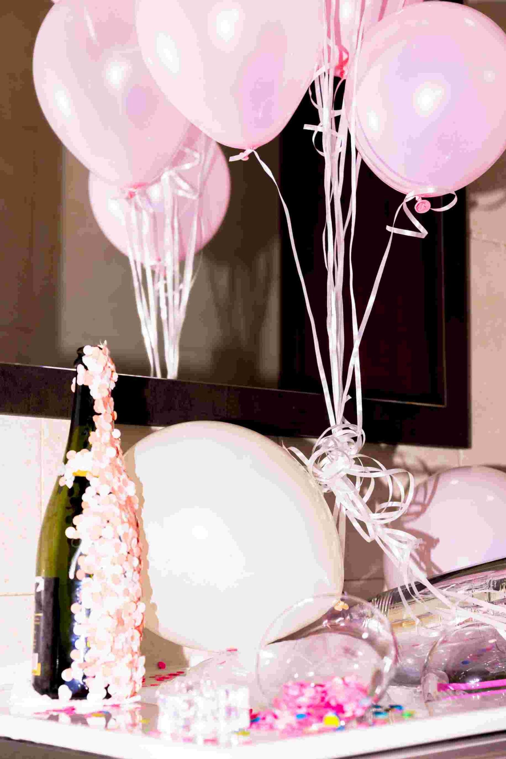 close up champagne bottle with confetti pink balloons desk