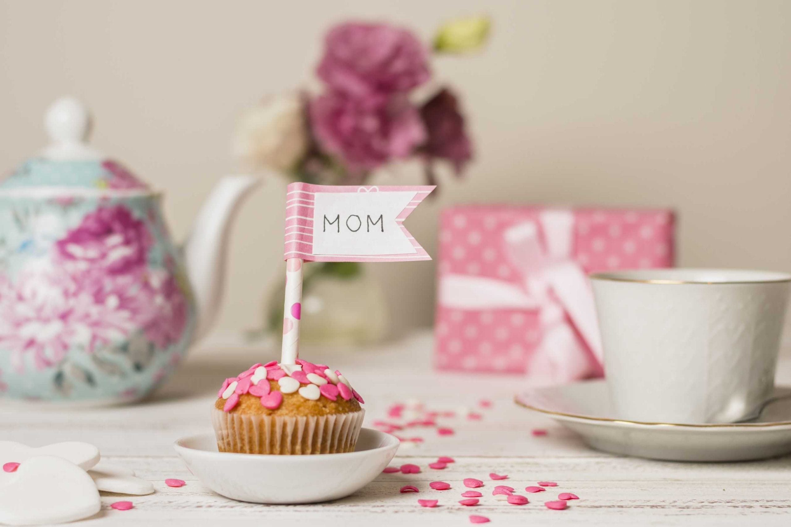 delicious cake with decorative flag with mom title near teapot cup