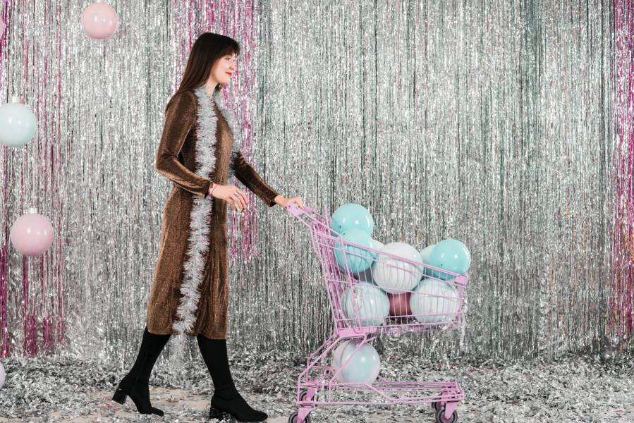 young woman with shopping trolley with decorative lamps near tinsel