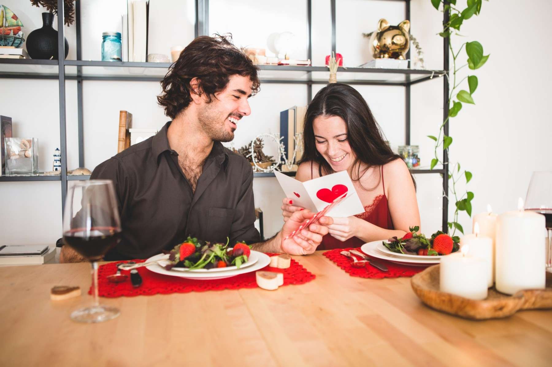 couple sitting table eat while she reads romantic postcard