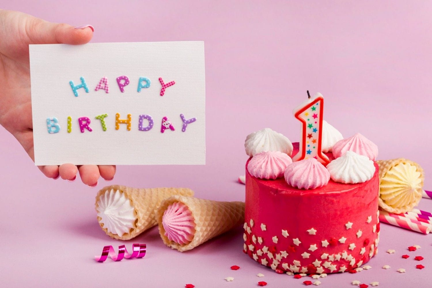 hand holding happy birthday card near decorative cake against purple backdrop