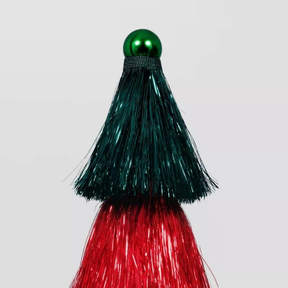 A decorative tree with a green colored top and red colored bottom, topped with a shiny green colored sphere.