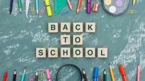 back-school-concept-with-wooden-cubes-magnifying-glass-school-supplies-plaster-background
