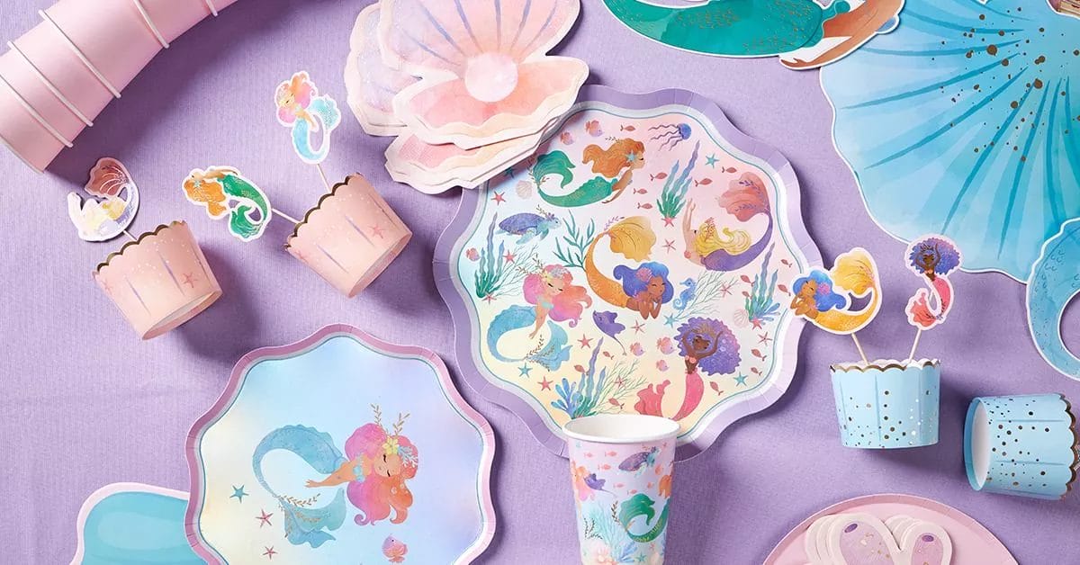 A magical underwater-themed set with scalloped plates, cups, and toppers featuring diverse mermaids, seashells, and pastel ocean colors.