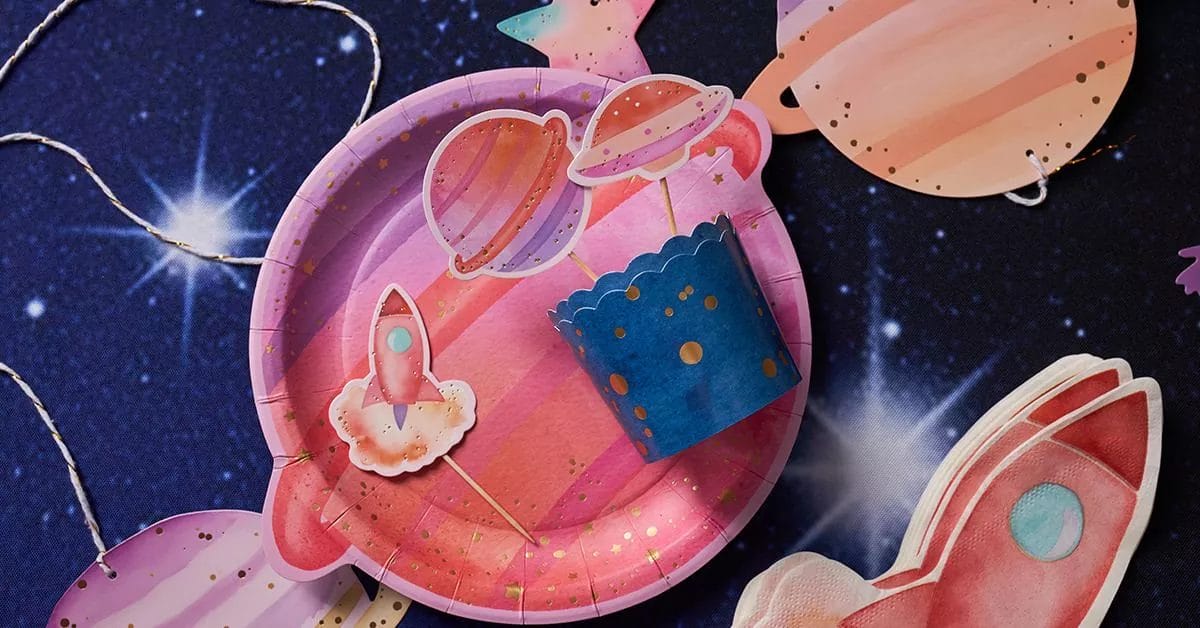 A whimsical cosmic arrangement with planet-shaped plates, rocket ship toppers, and starry decorations against a dark, star-filled background.