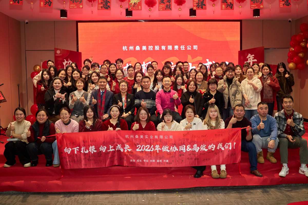 Group photo of Hangzhou Sunbeauty Holding employees at a 2026 company event, holding a red banner and giving thumbs up